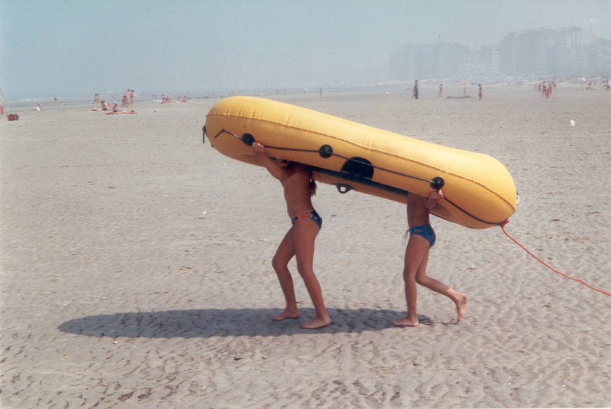 Kinderen op het strand op wandel met rubberen boot boven het hoofd